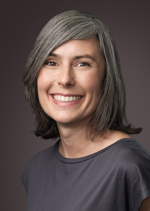 Business portrait of smiling lady in grey top with grey hair