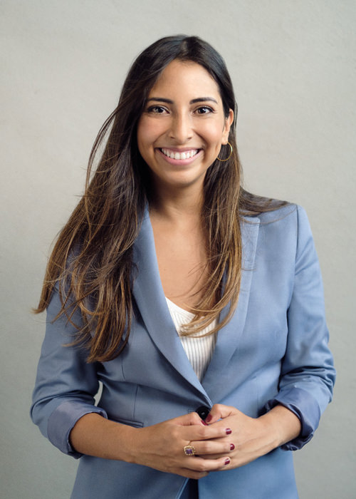 A portrait of a young south american professional woman wearing a blue suit and smiling